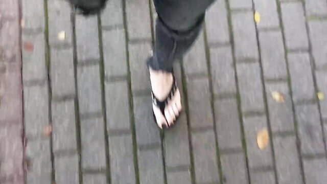 Slim crossdresser in ripped jeans and flip flops walking public street