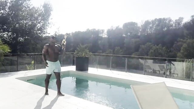 Muscular black man in tight light blue speedo by pool, huge BBC bulge