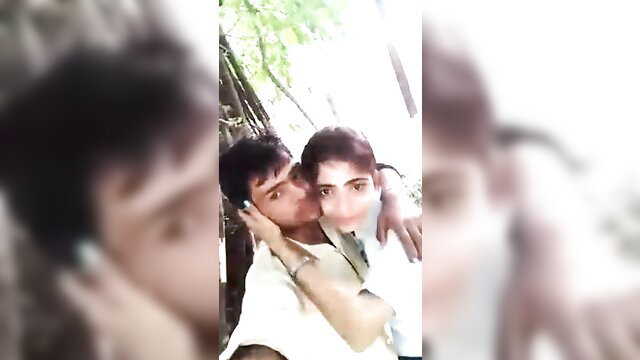 Young Desi couple passionately kissing outdoors in trees