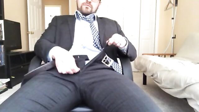 Man in suit unbuckling pants, seated bulge tease solo
