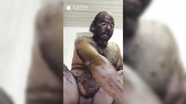Bald man covered in thick brown shit smears in scat fetish play