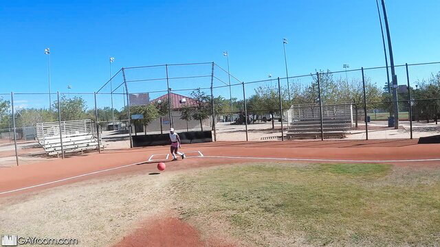 Hot brunette in shorts kicks red ball at sunny outdoor field