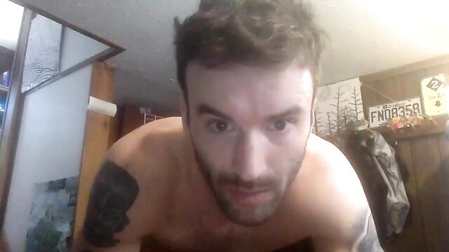 Shirtless tattooed white guy with beard leans in closeup selfie