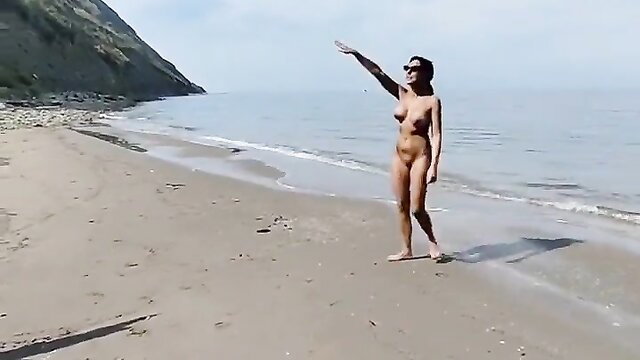 Nude tattooed brunette posing topless on sunny beach