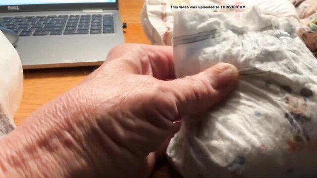 Closeup of hands holding open used small white adult diaper with cum stains