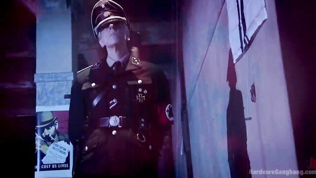 Nazi officer in SS uniform stands dominantly in hardcore gangbang scene