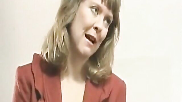 Blonde woman in red blazer smirking closeup, tickle fetish tease