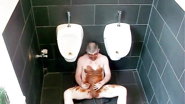Man covered in scat sits naked in men's room urinals