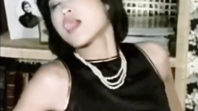 Vintage Asian maid sticks out tongue, wears pearl necklace in sexy black dress