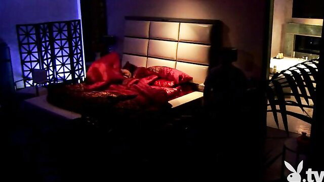 Red sheets on bed in steamy bedroom, Playboy TV glow