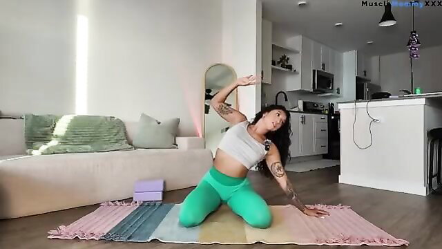 Tattooed Asian woman in tight yoga top and leggings, full body energizing pose