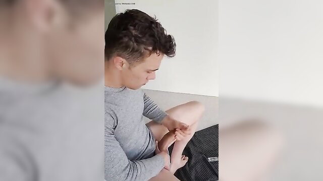 Young man in gray long sleeve touching his bare foot solo tease