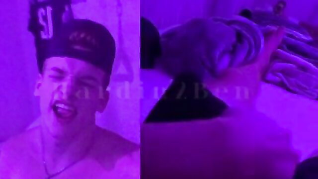 Hot young white guy in hat shirtless, feet and bulge in purple-lit gay jerk scene