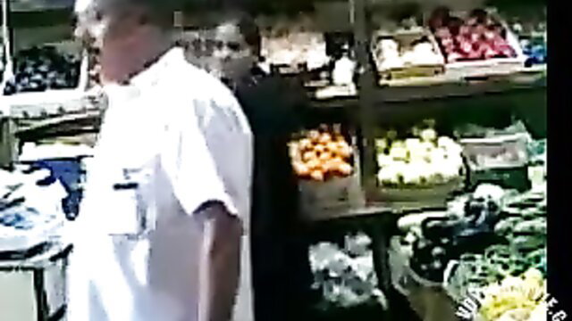 Man in white shirt flirts with woman behind Turkish store produce counter