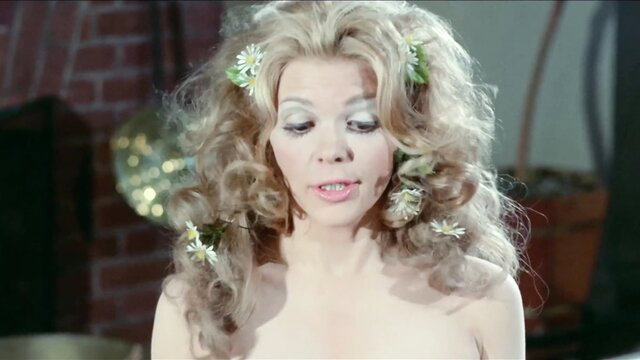 Blonde bombshell with daisies in wild hair, topless retro tease