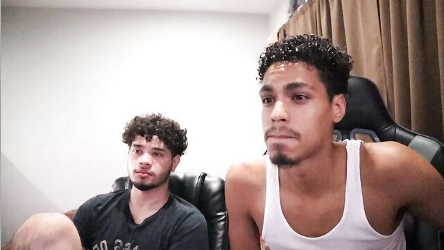 Two curly-haired Latino twinks in tank tops on chairs, amateur gay thumbnail