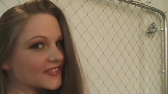 Regan Starr in chain link cage, seductive gaze, adult video thumbnail