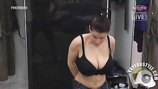 Busty brunette reality TV girl in black bra getting dressed in locker room