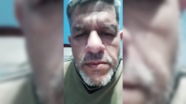 Closeup of mature Latino man with gray beard smirking in adult video thumbnail