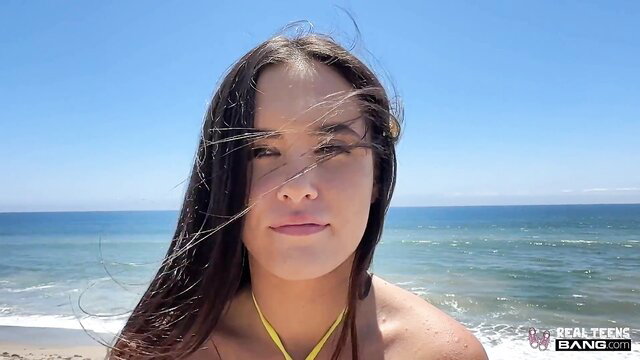 Daisy Phoenix topless at beach, long dark hair blowing in wind