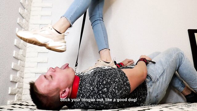 Dominatrix in jeans and sneakers commands sub to stick tongue out on floor