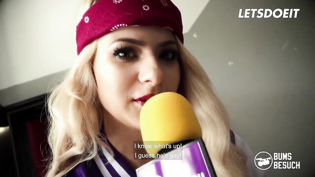 Lilli Vanilli blonde with red bandana holds mic in sexy sailor uniform