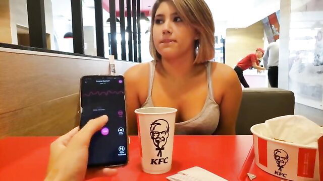 Petite blonde babe in tank top at KFC table with phone app