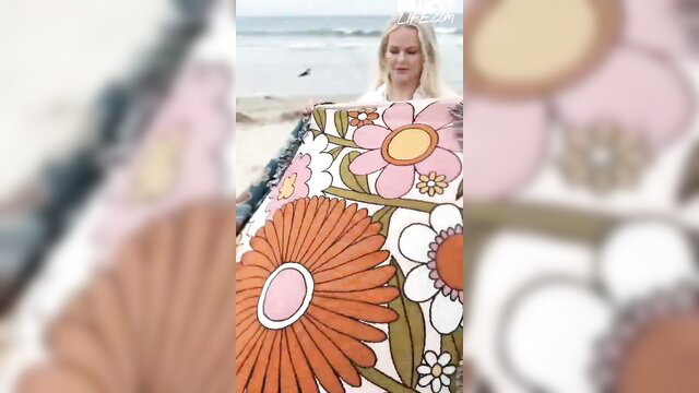Slimthick Vic holds colorful beach blanket at California shore