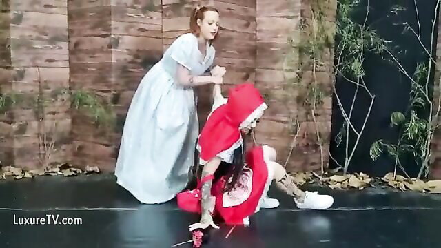 Red Riding Hood in red cape gagged by woman's foot in sexy dress