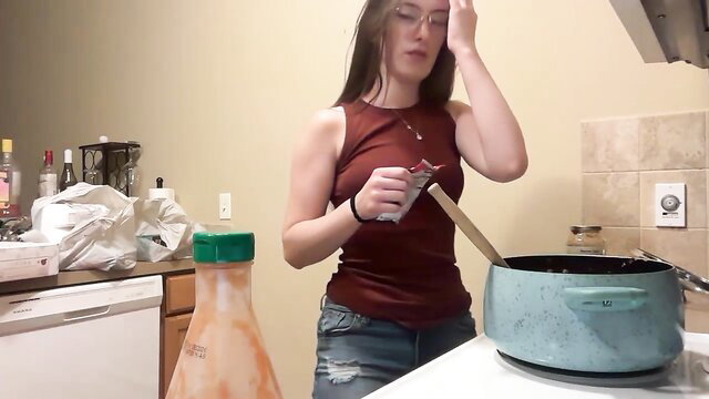 Brunette camgirl cooking topless in tank top and jeans on Chaturbate