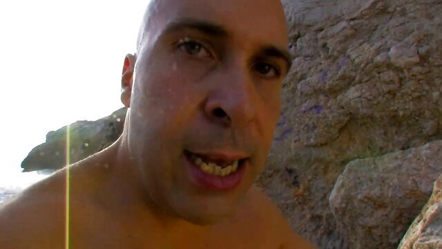 Bald Angell Summers nude on rocky beach, hardcore gambling tease