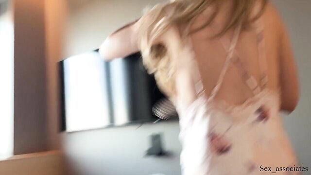 Blonde stepmom in white backless dress dances seductively on hotel bed