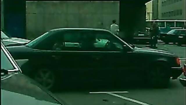 Outdoor parking lot scene with black Mercedes car, people nearby