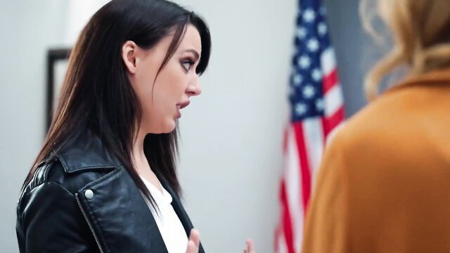 Erica Cherry in leather jacket looking shocked, American flag background