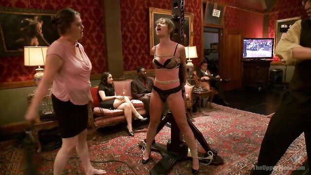 Blonde bound in lingerie on fucking machine at BDSM orgy party