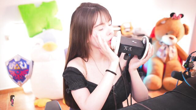 Asian gamer girl with long black hair licks wet ear in headphones closeup