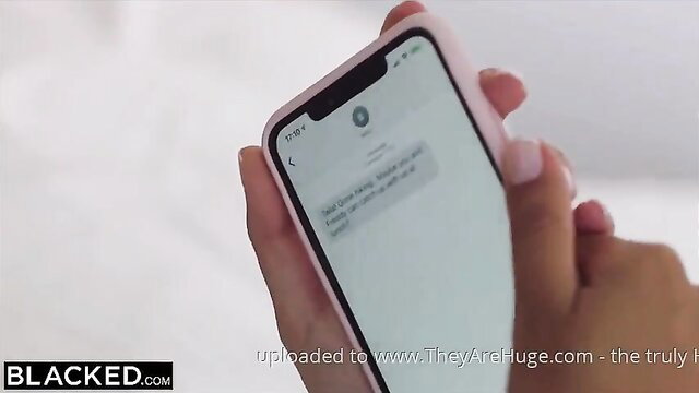 Shy Talia holds pink iPhone showing text, seducing crush on Blacked holiday