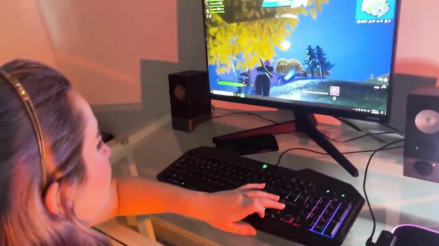 Hot Asian gamer girl with headset plays Fortnite at PC setup