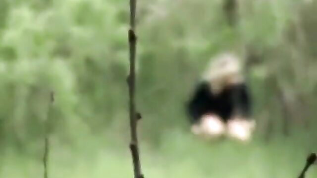 Blurry zoom on blonde woman peeing in woods while others wait
