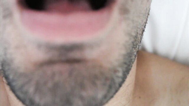 Closeup of bearded man's open mouth and stubble in erotic tease