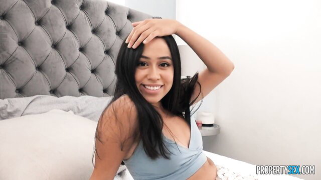 Dania Vega smiling in tank top on bed