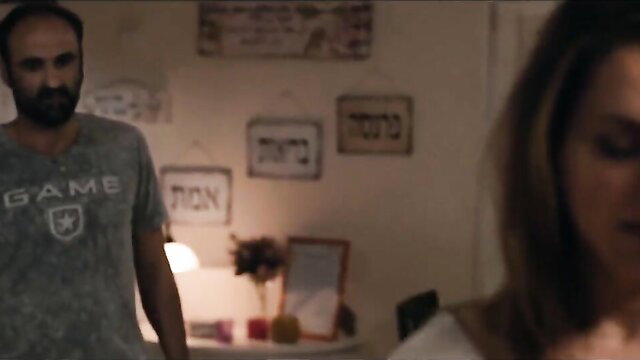 Liat Ekta as Sima in Noble Savage: busty brunette stares at man in GAME tee