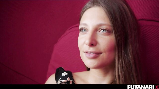 Talia Mint lounging seductively in black lingerie on red couch