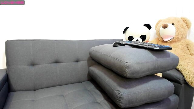 Woman on gray couch with TV remote and stuffed panda bear toy