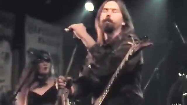 Long-haired rocker guy and masked goth girl rocking guitars on stage
