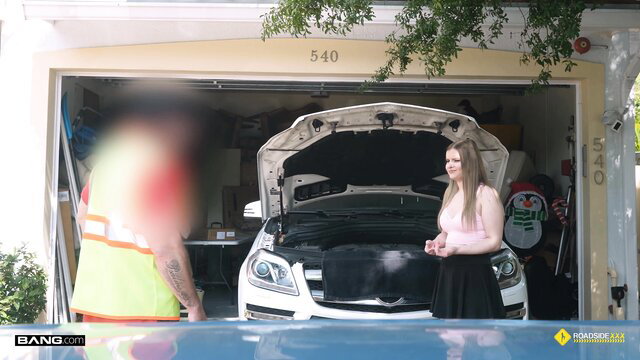 Blonde in pink top and skirt with mechanic under car hood