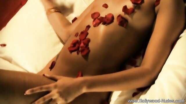 Nude Indian girlfriend covered in red rose petals on bed
