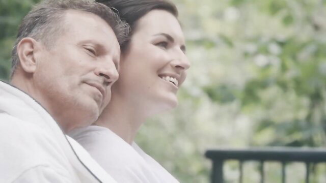 Jennifer Jane smiles intimately with older man in outdoor retreat