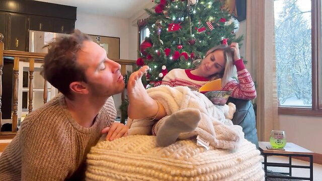 Christmas femdom foot fetish: man kissing woman's socked foot on couch
