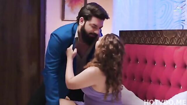 Bearded Indian man kissing curvy brunette woman on bed in hot web series